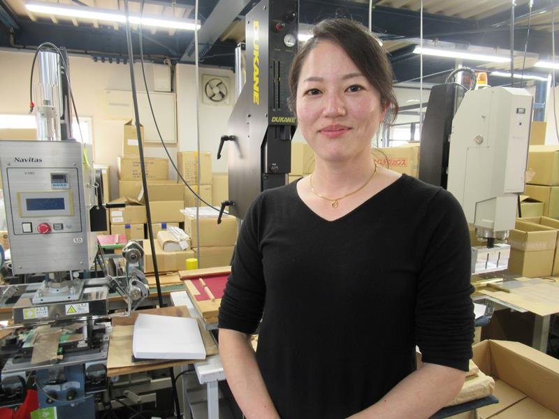 ファイルのシートを貼り付ける機械が並ぶ作業場での永田社長＝鎌ケ谷市
