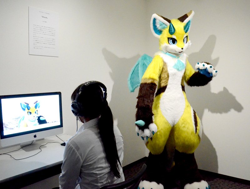 卒業作品の一つであるミュージックビデオを視聴する学生。卒業生によるオリジナルの着ぐるみ（右）が出演している＝東金市