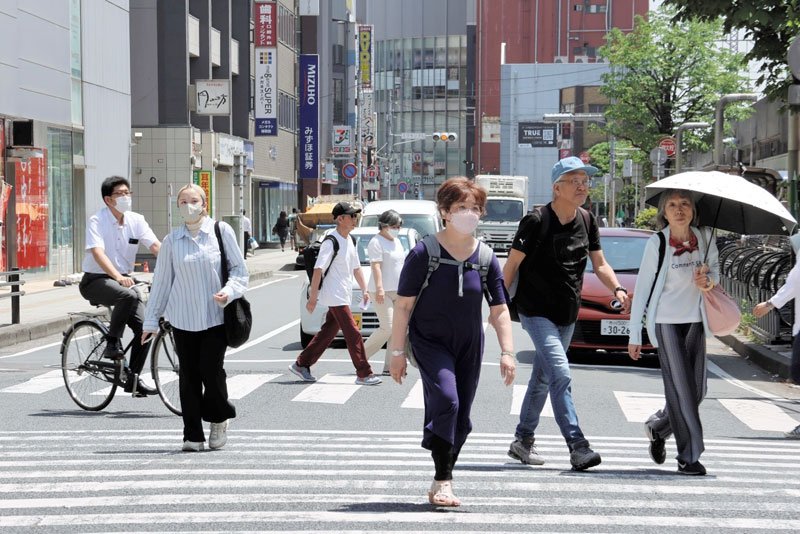 千葉市内でも気温が上がり、半袖姿や日傘を差して歩く人が見られた＝１７日午後０時２５分、同市中央区の交差点
