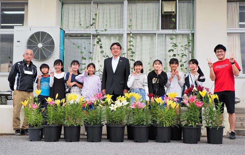 色とりどりに開花したユリと栽培飼育委員会の６年生ら。粕谷智浩市長（中央）も観賞に訪れた＝袖ケ浦市
