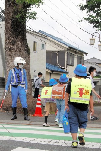 葛飾小学校前で登校する児童を見守る交通機動隊員＝２６日午前７時４５分ごろ、船橋市
