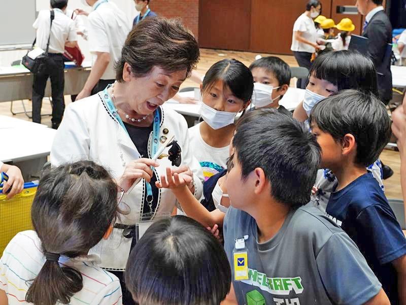 会場で自然羽化したクロアゲハを小学３年生たちに見せる照川市長＝勝浦市
