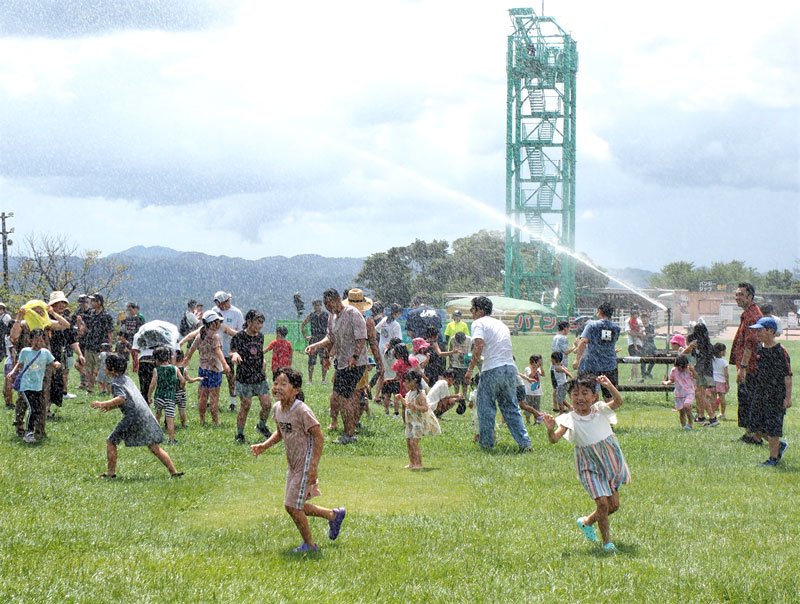 山の上の草原で水遊びイベントに大はしゃぎの子どもたち＝２７日、富津市のマザー牧場
