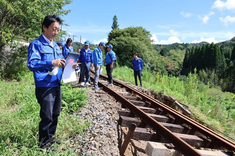 土砂崩れの被害があったいすみ鉄道の線路を視察する滝田政調会長（左）ら＝１４日午後、大多喜町
