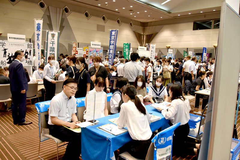 学校のブースで説明を受ける来場者ら＝１８日、千葉市美浜区