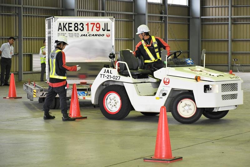 コンテナをつないだけん引車を運転し、障害物をかわす技術を見せるＪＡＬグランドサービスのペア＝成田空港
