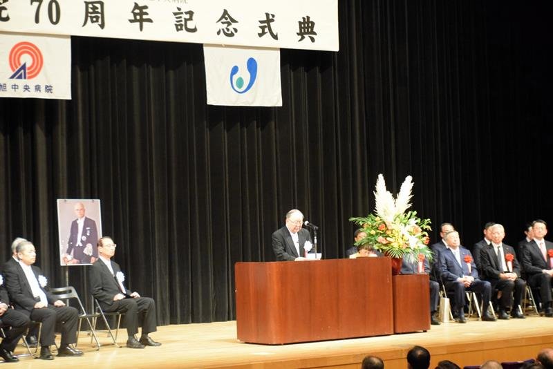 病院関係者や来賓、市民らが出席した記念式典であいさつを述べる吉田理事長＝１４日、旭市
