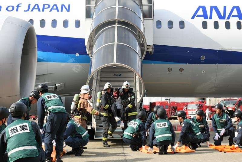 成田空港で炎上したと想定した航空機から旅客を救助する訓練をする消防隊員ら＝成田市
