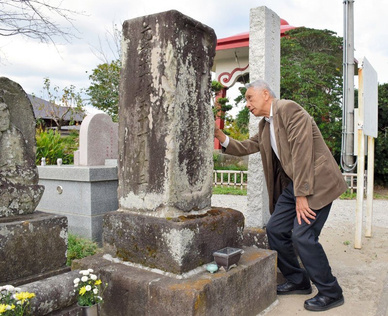 元禄地震の供養碑を説明する古山豊さん。石碑や古文書を分析し被害の実像に迫ってきた＝長生村
