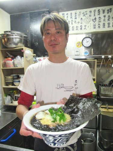 「三番瀬海苔ラーメン」を手にする店主の山西さん。ラーメン専門誌の表紙に登場したことも＝市川市
