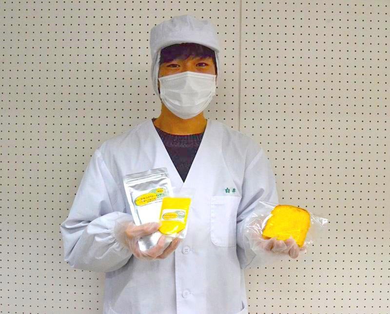 カボチャを加工したパウダー（左）や、パウダーを練り込んで作ったパンを持つ学生＝東金市
