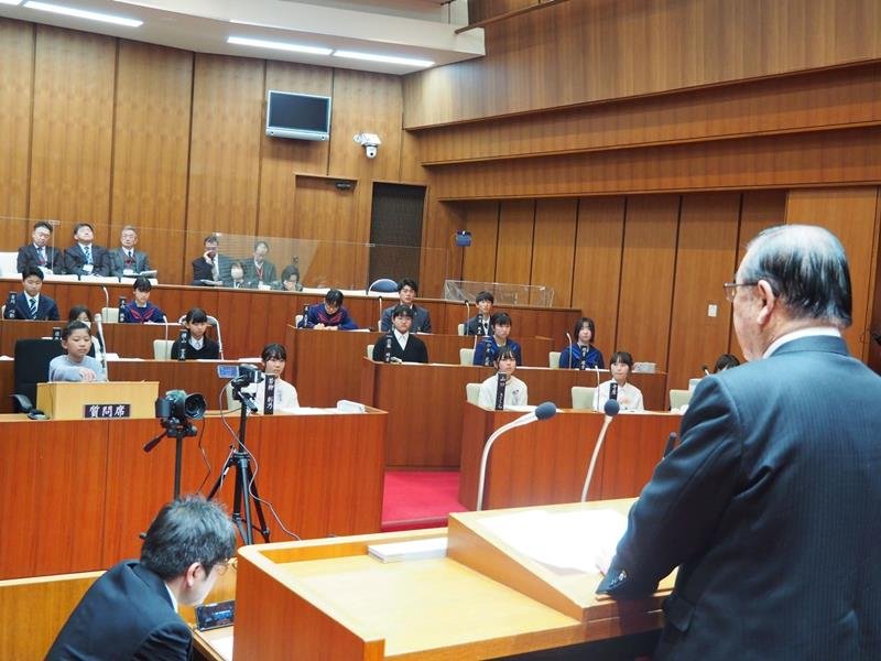 模擬議会で北村新司市長（手前）の答弁を聞く子ども議員＝八街市議会議場（同市教委提供）
