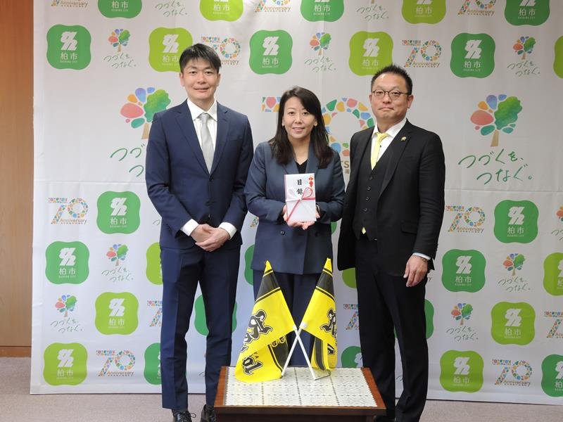 集まった寄付金の目録を太田市長（中央）に渡したレイソル後援会の鴇田実行委員長（右）と近藤さん＝柏市役所
