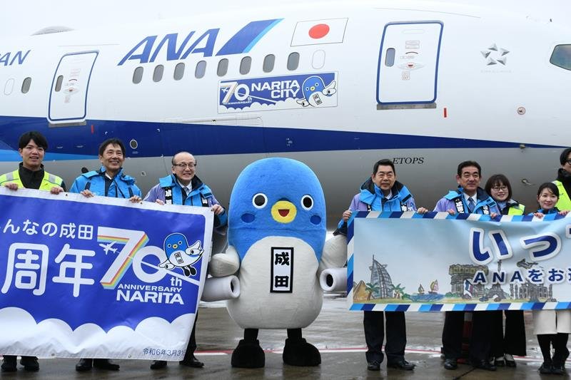 自分のイラストが入ったロゴマークが貼られた機体を紹介するうなりくん（中央）ら＝２月２３日、成田市の成田空港

