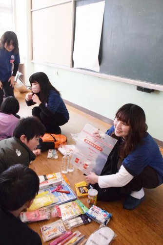 災害時に持ち出すリュックサックの中身を紹介するメンバー。子どもたちは興味津々＝９日、銚子市