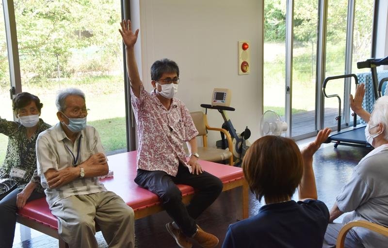 通所リハビリの入所者とコミュニケーションを図る松永医師（中央）
