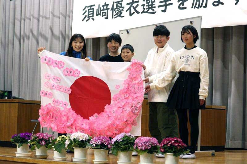 花びらを模した紙に書かれた応援メッセージの寄せ書きを母校の在校生たちから受け取り笑顔の須崎選手＝１１日、松戸市（同市提供）