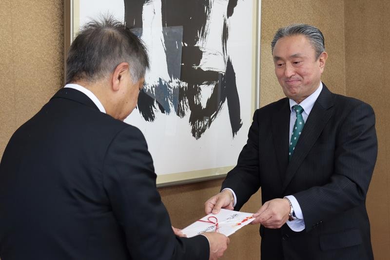 寄付金の目録を手渡す市原会長（右）
