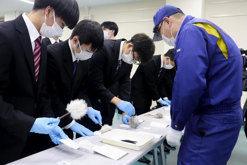船橋東署で、警察官の指導を受けながら鑑識作業を体験をする学生たち
