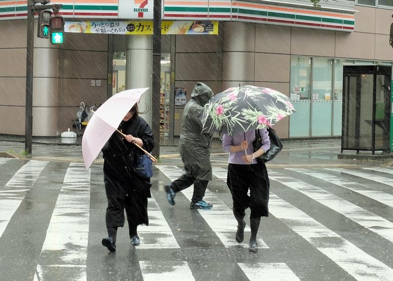 強い風の中、傘を支えながら横断歩道を渡る人たち＝９日、千葉市中央区
