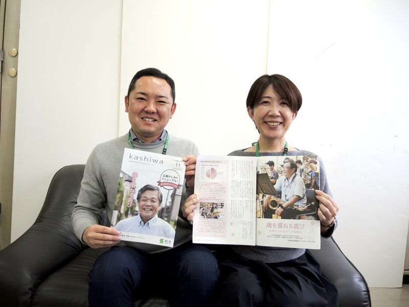 県広報コンクールで最優秀となった「広報かしわ」を手にする担当職員。左がリーダーの落合さん＝柏市