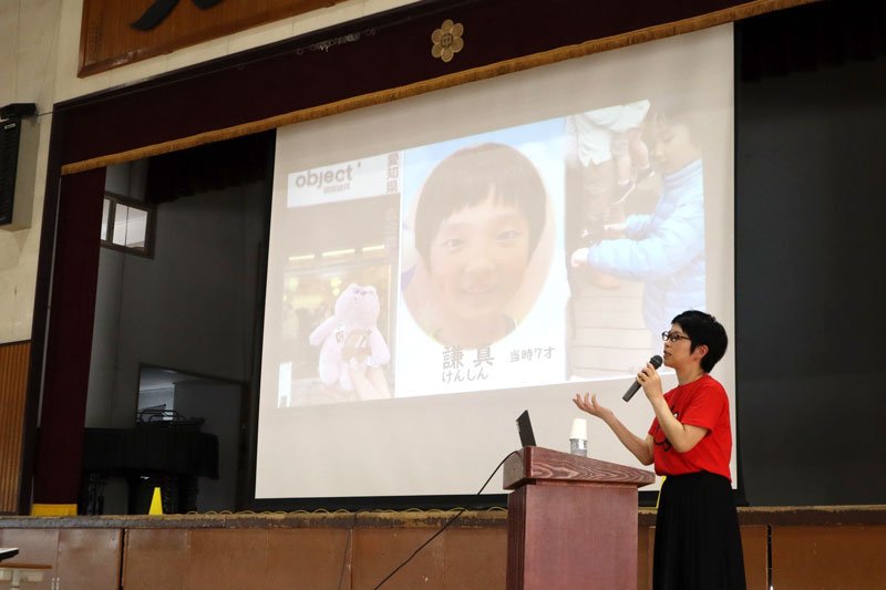 スクリーンに映し出された謙真君の写真の前で講演する高田さん＝１７日午後、船橋市立二宮中学校