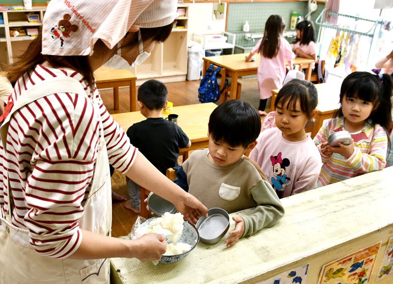 子どもたちの弁当箱にご飯を盛る保育士＝１８日、神崎町立米沢保育所