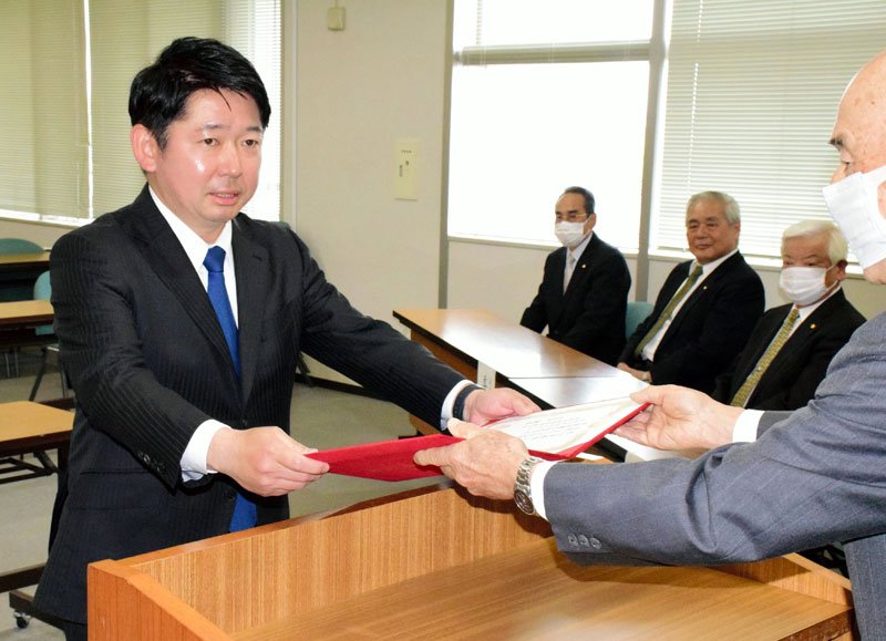 激戦の勝利から一夜明け、当選証書を受け取る市原淳氏（左）＝２２日、茂原市役所
