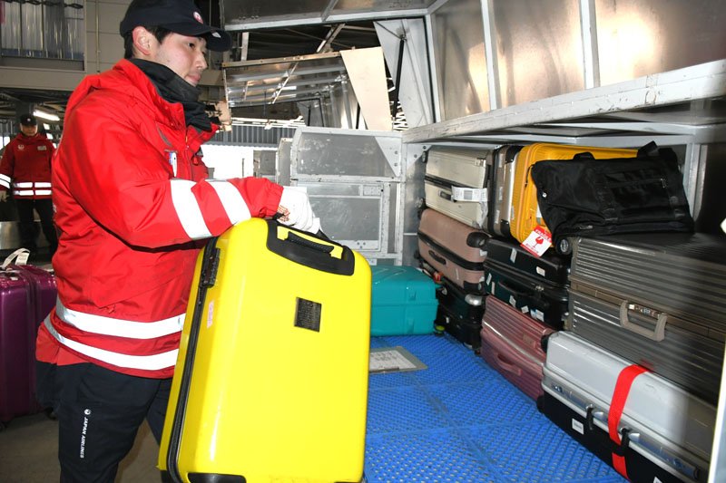 成田空港の駐機場で航空機に搭載するコンテナに旅客から預かった手荷物を積み込む谷奥さん＝成田市