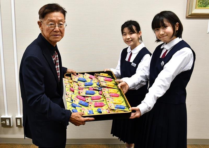 小見川中の女子生徒に防犯ブザーを贈った小山田会長（左）＝香取市

