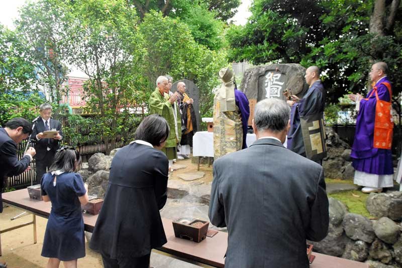江戸時代に今の和歌山県から移住し、銚子の発展を支えた先祖らの功績をたたえる「紀國人移住碑」の前で手を合わせる参列者ら＝６日、銚子市