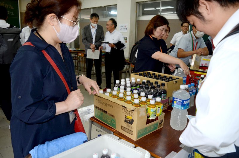 千葉県立九十九里高で初めて開催された「校内居場所カフェ」で、フードバンクなどで集めた飲料を生徒に配る町職員ら＝九十九里町