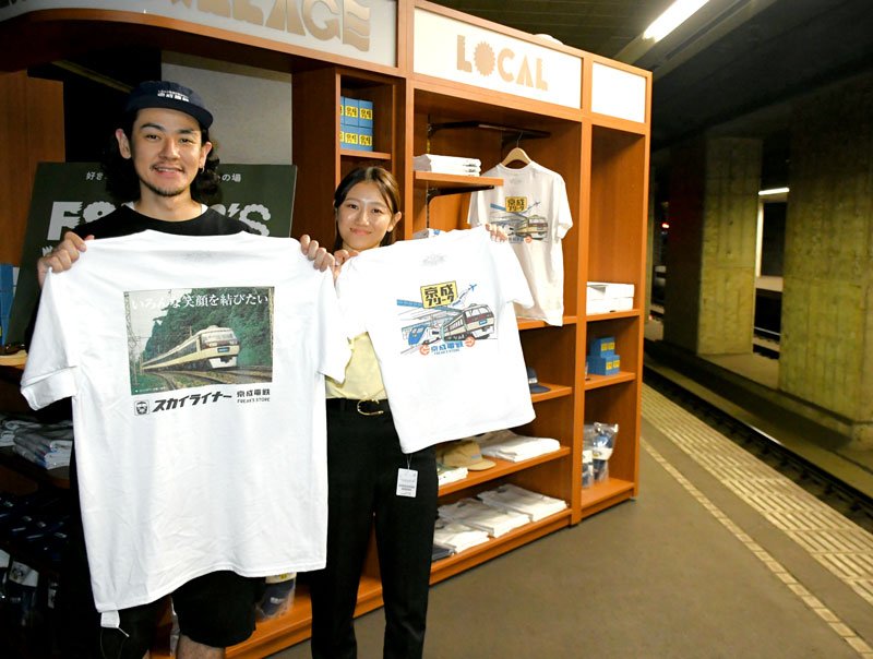 旧成田空港駅の廃止されたホームで特別販売するスカイライナーのデザインＴシャツを紹介するスタッフ＝２１日、成田市