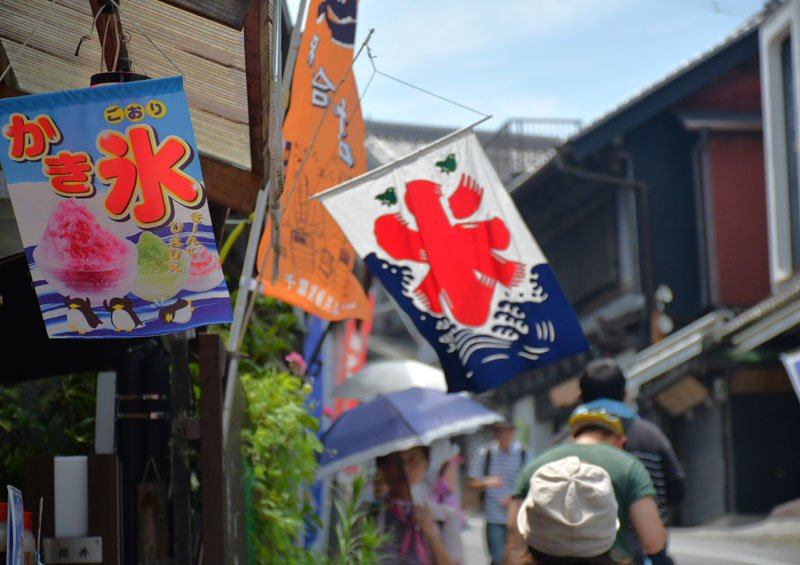 すでに気温３５度以上の猛暑日となった成田市。日傘や帽子で暑さ対策をして歩く人の姿が目立つ＝２４日