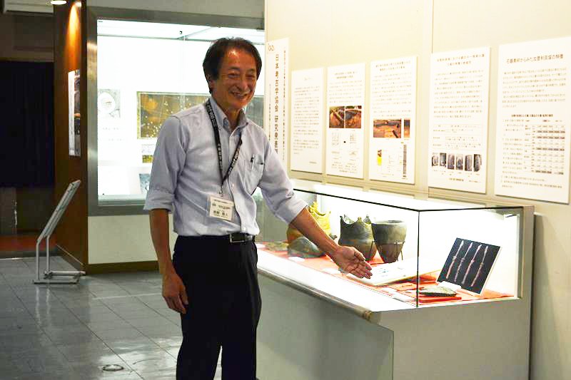 研究成果についての展示を紹介する千葉市埋蔵文化財調査センターの西野所長＝同市若葉区の加曽利貝塚博物館