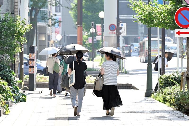 夕方近くになっても多くの人が日傘を差し、暑さをしのいだ＝８日午後３時４０分、千葉市中央区
