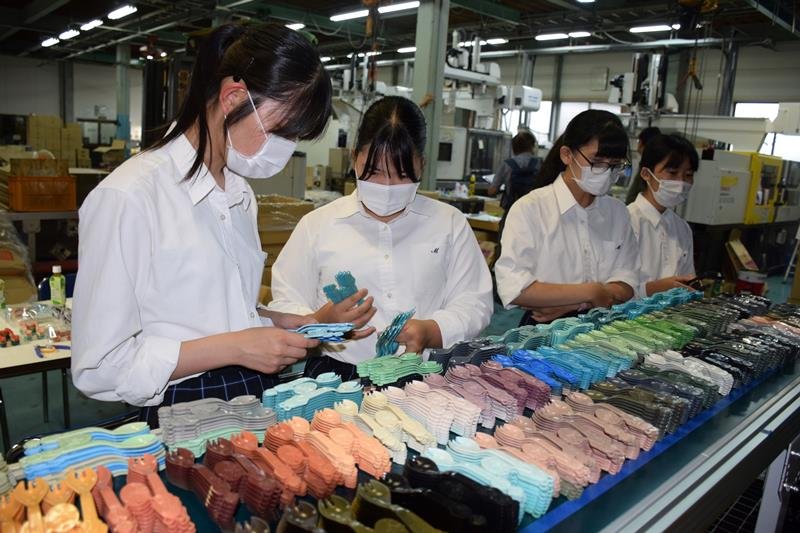 製造工場を訪ね、完成したスプーンを手に取る茂原高校の生徒たち＝１２日、茂原市
