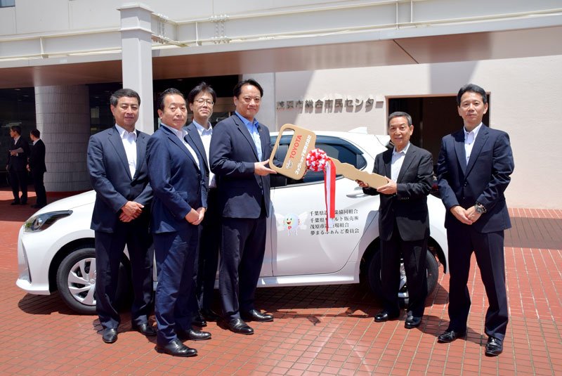 福祉車両の前で、レプリカキーを鬼島会長（右から２人目）に手渡す星山理事長＝茂原市