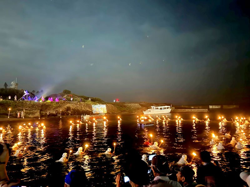 たいまつを持って円を描くように泳ぐ海女さんたち＝２０日夜、南房総市