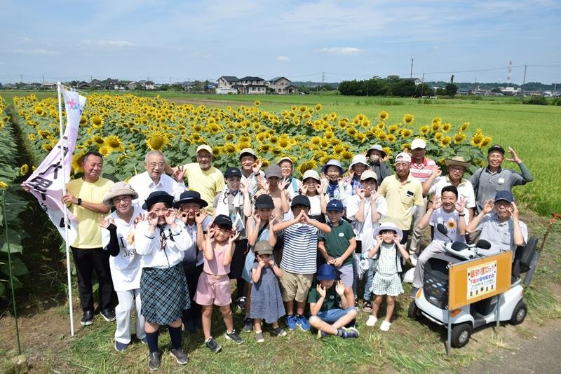 満開になったヒマワリ畑と地元の下富谷地区住民や関係者＝２７日、匝瑳市

