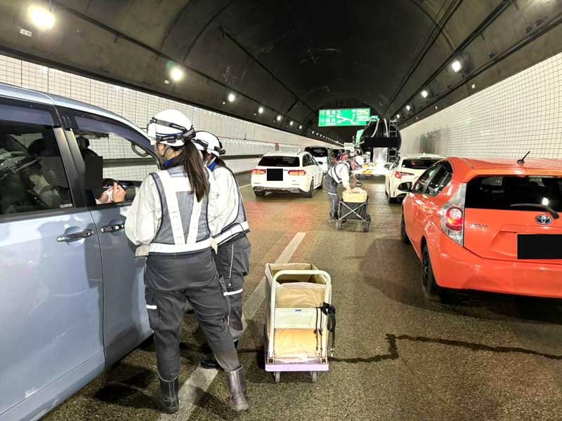 ネクスコは事故のあったアクアライントンネル上り線で待機中のドライバーらに軽食、飲料水、簡易トイレ等を配布した＝２８日夕（ネクスコ東日本のＸ）