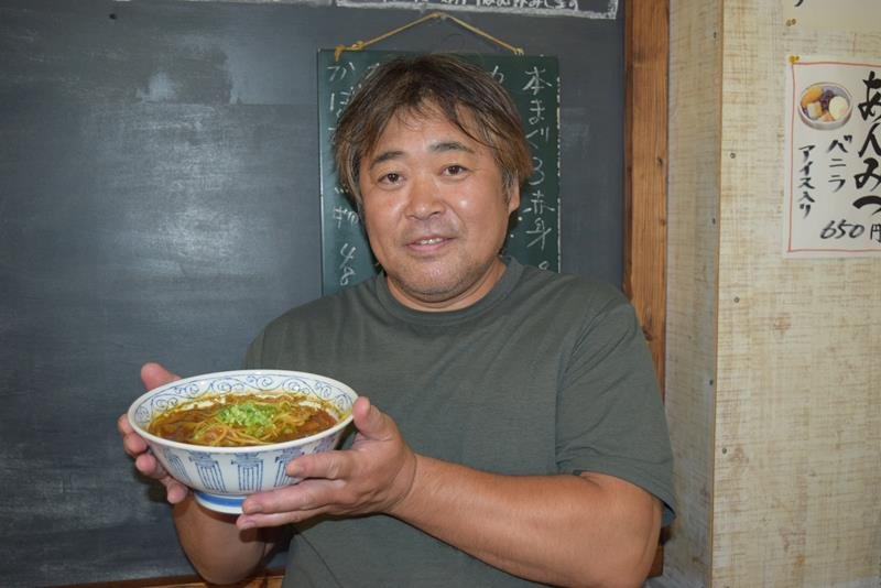 辛さと梨の甘さが絶妙にマッチした「カレータンタンメン」を手にする本田さん＝八千代市
