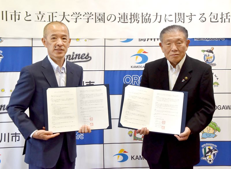 協定書を掲げる長谷川市長（右）と生駒理事長＝鴨川市役所