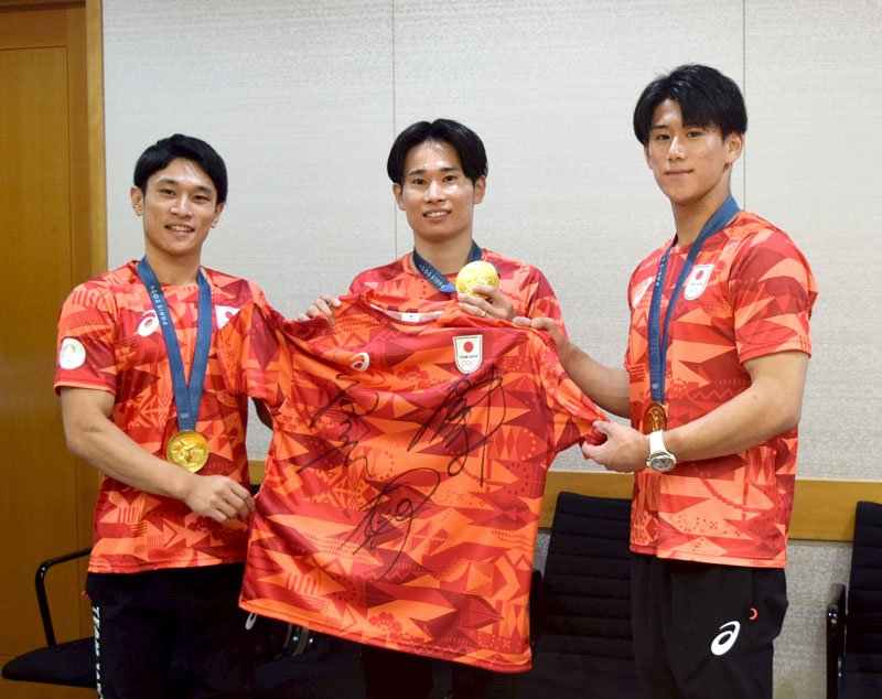 サイン入りユニホームを掲げる（左から）谷川選手、萱選手、橋本選手＝２日、船橋市役所