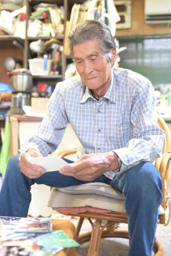 父が戦死したパプアニューギニアに赴いた時の写真を見る石井猛さん＝松戸市の自宅