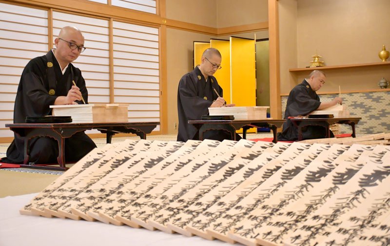 来年の正月用の護摩札へ丁寧に筆を入れて仕上げていく成田山新勝寺の僧侶＝１３日、成田市