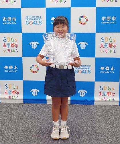 ＵＳキッズゴルフ世界選手権で連覇し、２つの優勝カップを抱える南さん＝市原市役所
