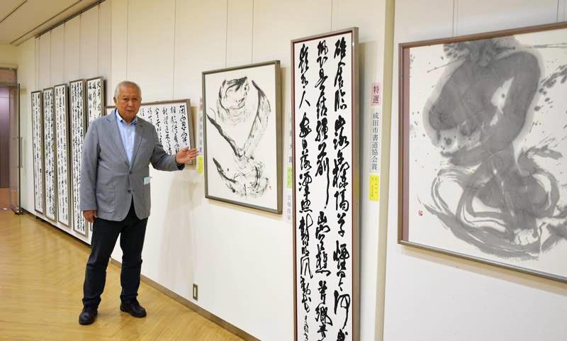 成田市書道協会展の受賞作品を紹介する山口会長＝同市