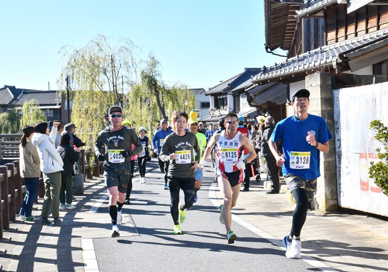 歴史的な建造物が立ち並ぶ佐原の町並みを駆け抜けるランナーら＝１５日、香取市