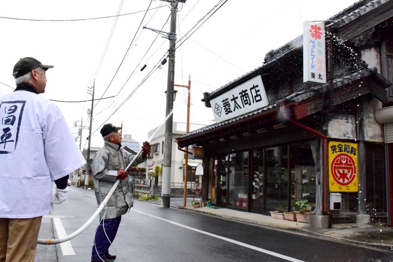 防火を願い家屋に水をかける昌平町の住民＝１２日、茂原市
